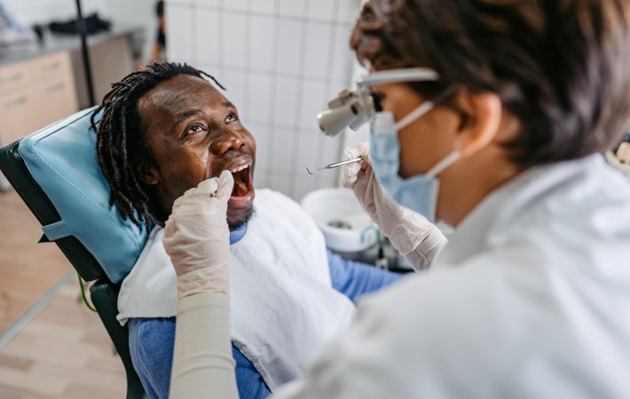Dental team member in mask examines teenager's teeth